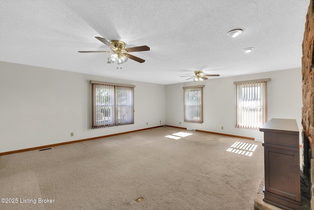 unfurnished room with a ceiling fan, visible vents, baseboards, a textured ceiling, and light colored carpet