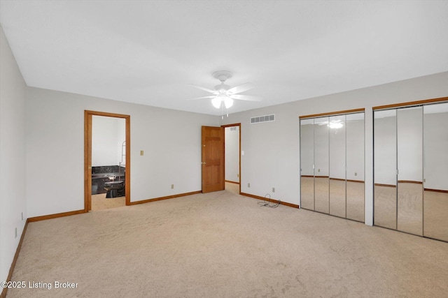 unfurnished bedroom with visible vents, carpet floors, two closets, and baseboards