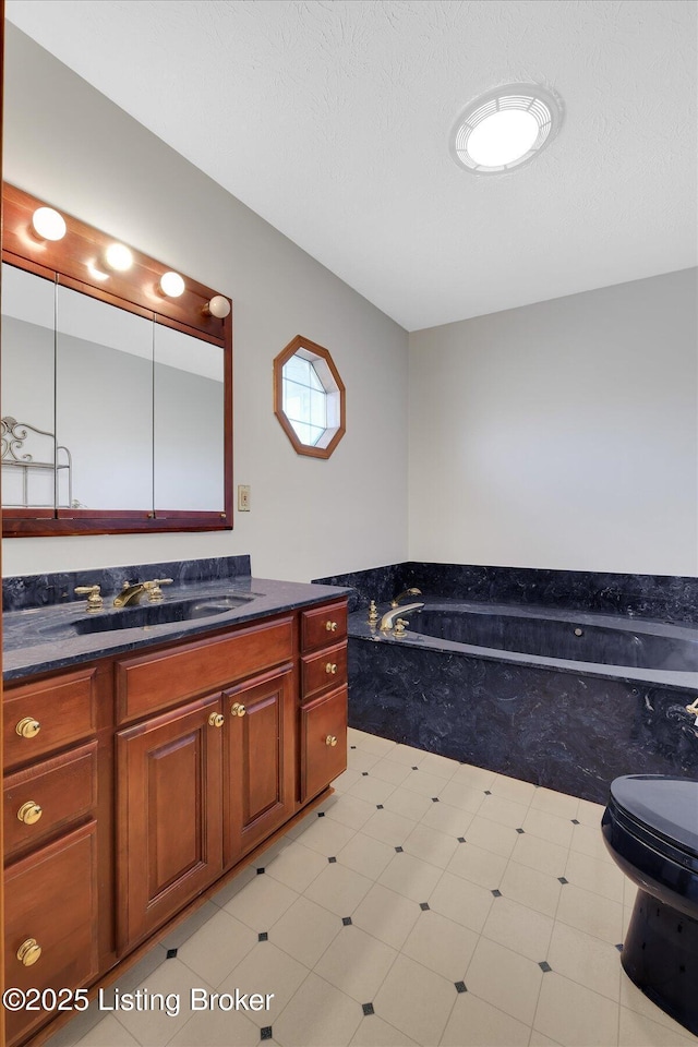 full bathroom with vanity, a garden tub, and a textured ceiling