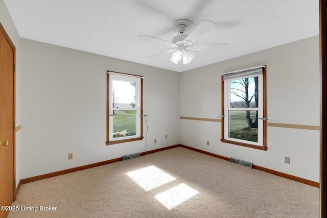 carpeted spare room featuring baseboards, visible vents, and a wealth of natural light