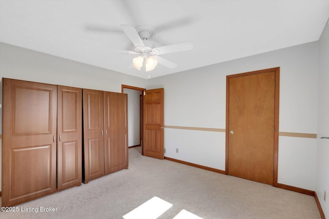 unfurnished bedroom with a ceiling fan, baseboards, a closet, and light carpet