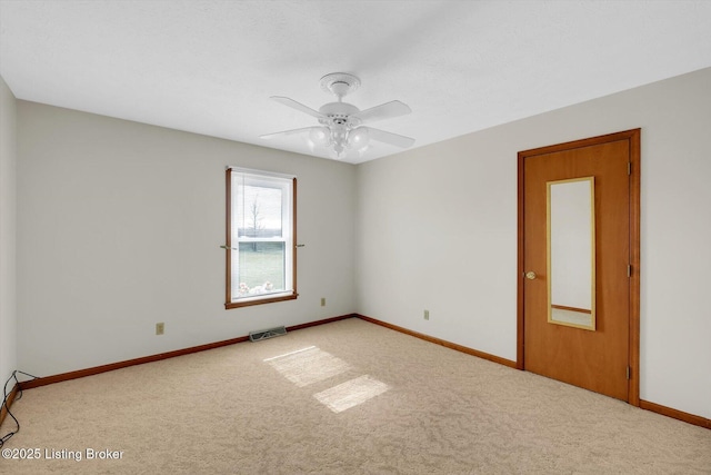 spare room featuring carpet, baseboards, visible vents, and a ceiling fan