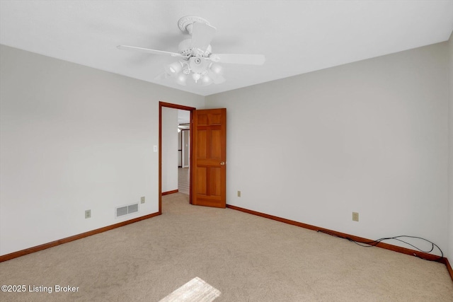 carpeted spare room with visible vents, baseboards, and a ceiling fan