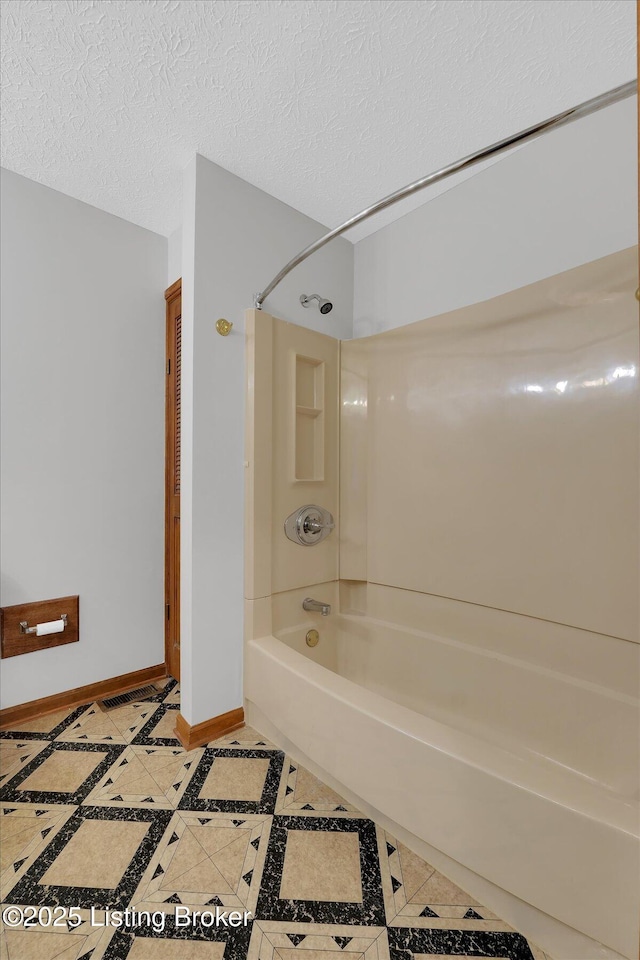 full bath featuring baseboards, a textured ceiling, bathtub / shower combination, and tile patterned flooring