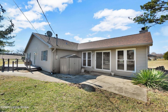 back of property featuring a lawn, a deck, a patio, an outdoor structure, and a chimney