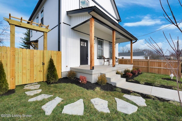 doorway to property with a porch, a yard, and fence