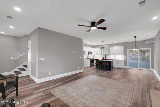 living room with wood finished floors, visible vents, and baseboards