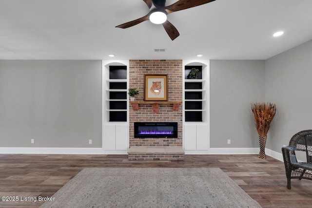 living room featuring visible vents, built in shelves, baseboards, and wood finished floors