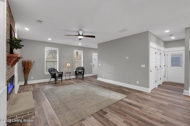 unfurnished room featuring visible vents, baseboards, recessed lighting, wood finished floors, and a glass covered fireplace