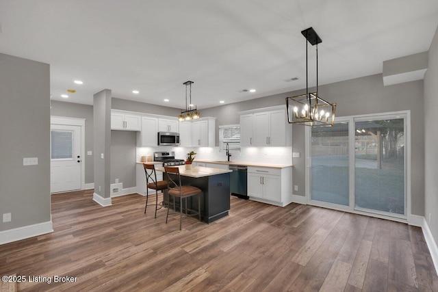 kitchen featuring a center island, appliances with stainless steel finishes, white cabinetry, and wood finished floors