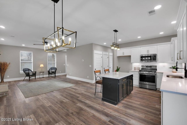 kitchen with a sink, dark wood finished floors, white cabinetry, stainless steel appliances, and light countertops