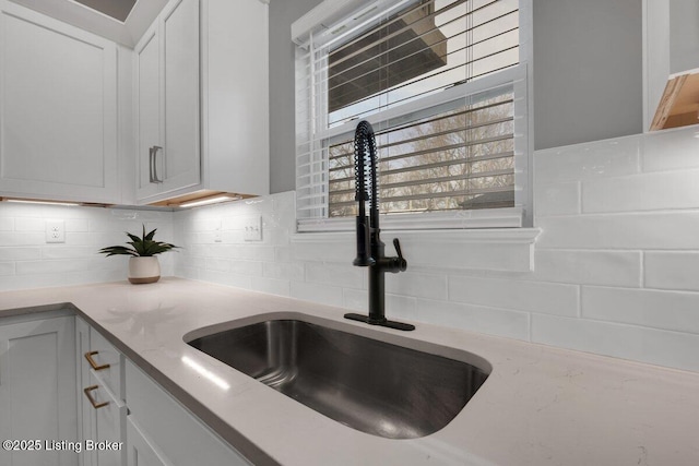 kitchen with a sink, decorative backsplash, and light stone counters