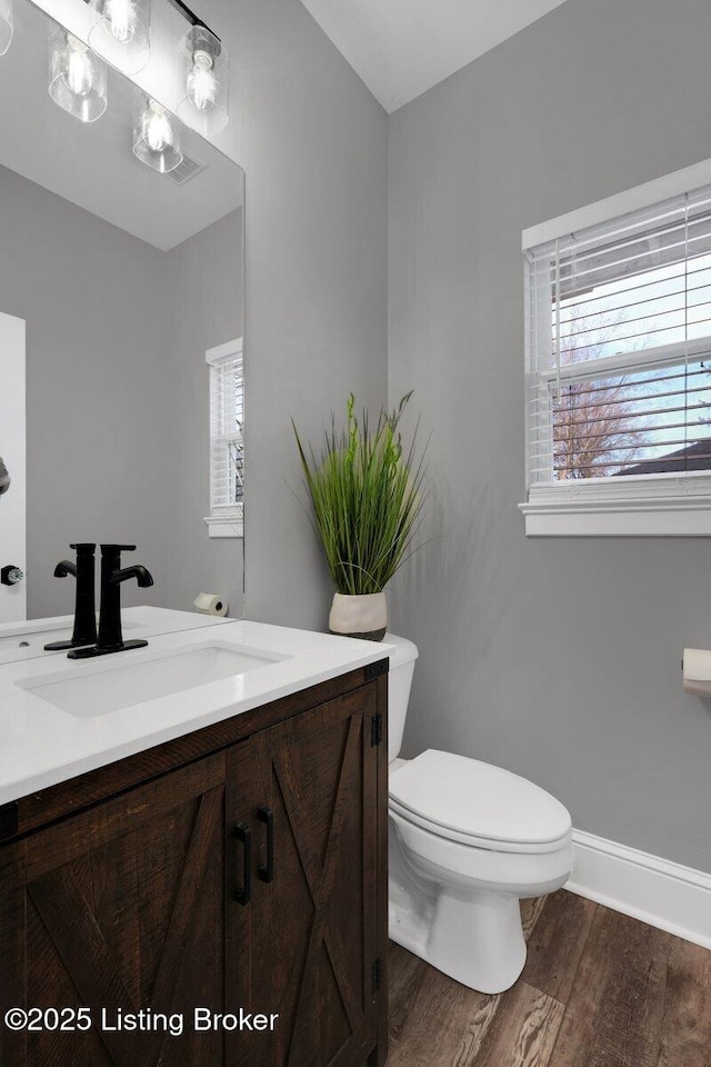 bathroom featuring a wealth of natural light, toilet, wood finished floors, and vanity