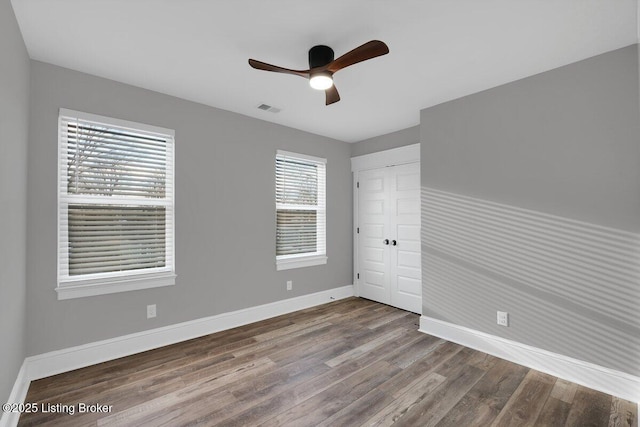 unfurnished bedroom with wood finished floors, visible vents, baseboards, ceiling fan, and a closet