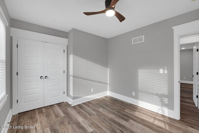 unfurnished bedroom featuring a closet, visible vents, baseboards, and wood finished floors