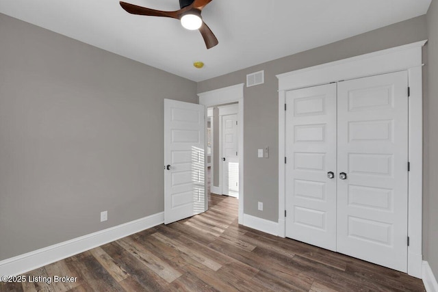 unfurnished bedroom featuring a ceiling fan, dark wood-style floors, visible vents, baseboards, and a closet