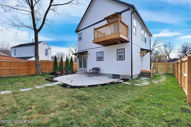 back of property with a balcony, a fenced backyard, a lawn, and entry steps