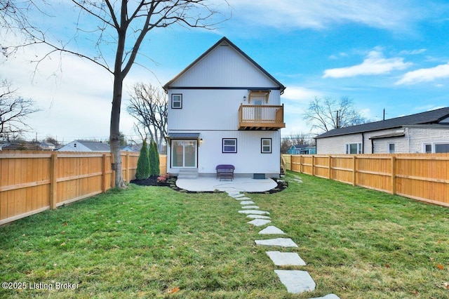 back of house featuring a balcony, a lawn, a patio, and a fenced backyard