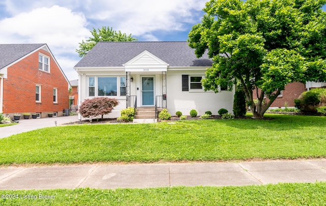 view of front facade with a front yard, brick siding, and a shingled roof