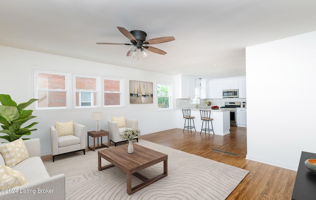 living room with light wood-style flooring and a ceiling fan