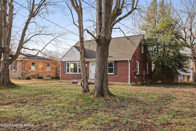 view of front facade featuring a front yard, brick siding, and roof with shingles