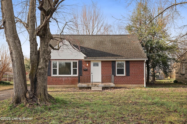 cape cod-style house with brick siding, a shingled roof, and a front yard