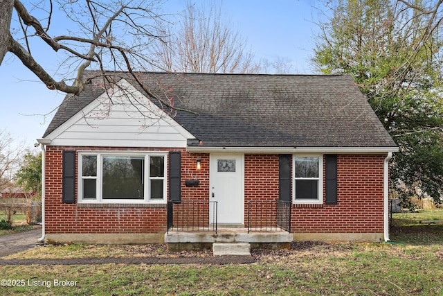 view of front facade with brick siding and a shingled roof