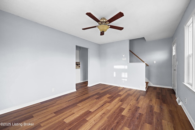 spare room featuring ceiling fan, stairway, baseboards, and wood finished floors