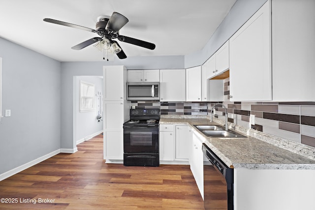 kitchen with black appliances, light wood-style flooring, a sink, white cabinetry, and decorative backsplash