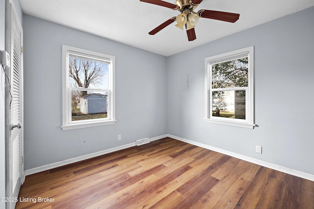 unfurnished room featuring visible vents, ceiling fan, baseboards, and wood finished floors