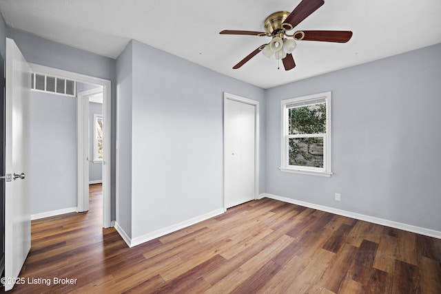 unfurnished bedroom featuring visible vents, baseboards, a closet, and wood finished floors