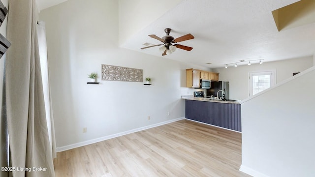 kitchen with baseboards, light wood finished floors, freestanding refrigerator, light countertops, and stainless steel microwave