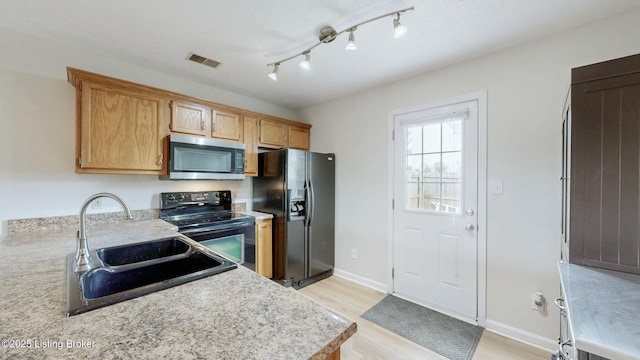 kitchen with black appliances, light countertops, visible vents, and a sink