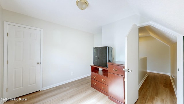 bedroom featuring baseboards, lofted ceiling, and light wood-style floors