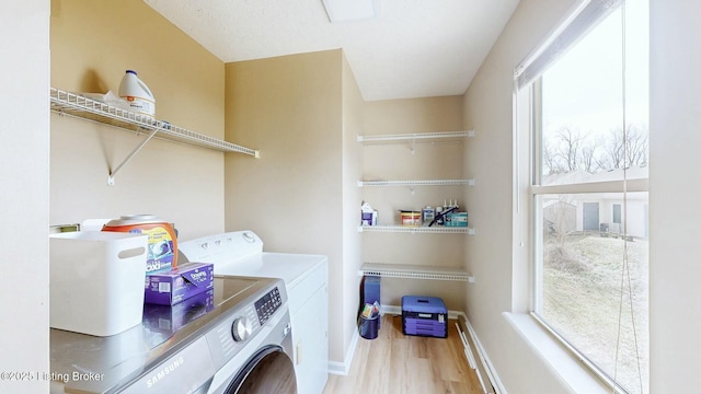 laundry area with laundry area, wood finished floors, separate washer and dryer, and a healthy amount of sunlight