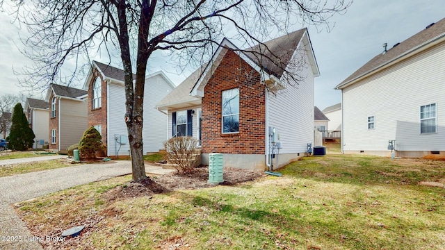 view of front facade featuring brick siding, cooling unit, aphalt driveway, and a front lawn