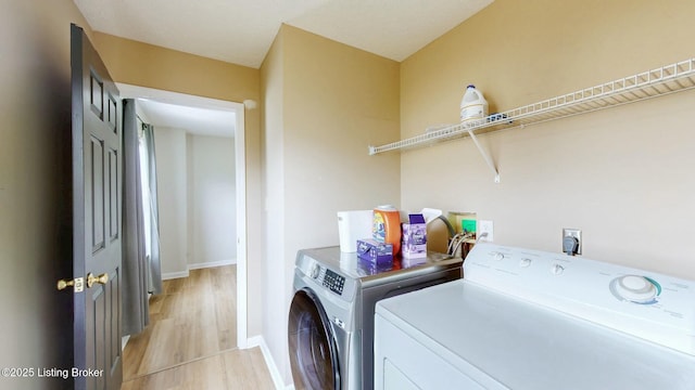 laundry area with laundry area, baseboards, independent washer and dryer, and light wood finished floors