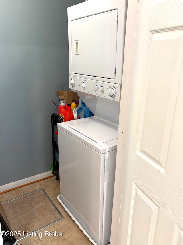 washroom with laundry area, stacked washer / dryer, light tile patterned floors, and baseboards