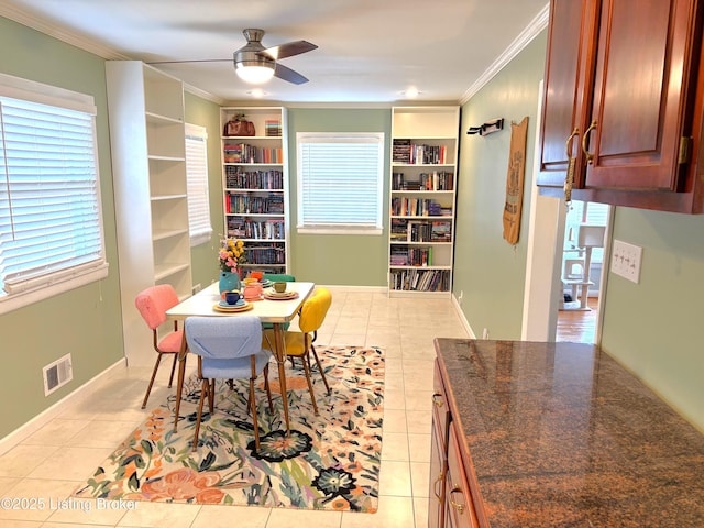 dining room featuring visible vents, ornamental molding, light tile patterned floors, baseboards, and ceiling fan