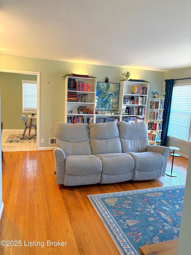 living room featuring visible vents, baseboards, and wood finished floors