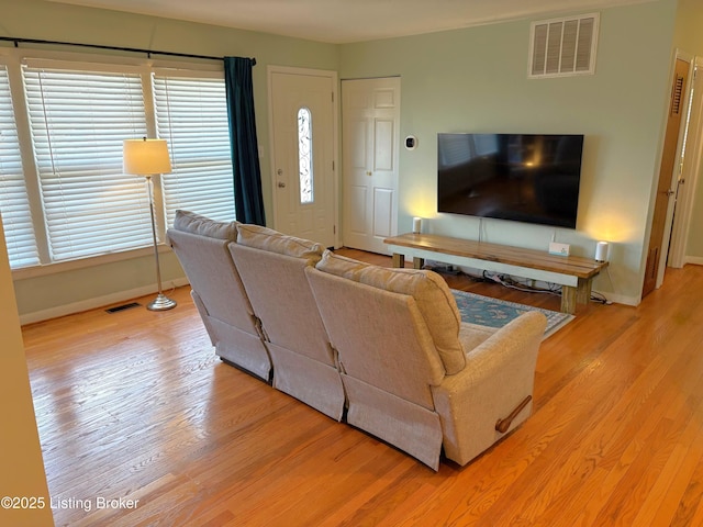 living area with wood finished floors, visible vents, and baseboards