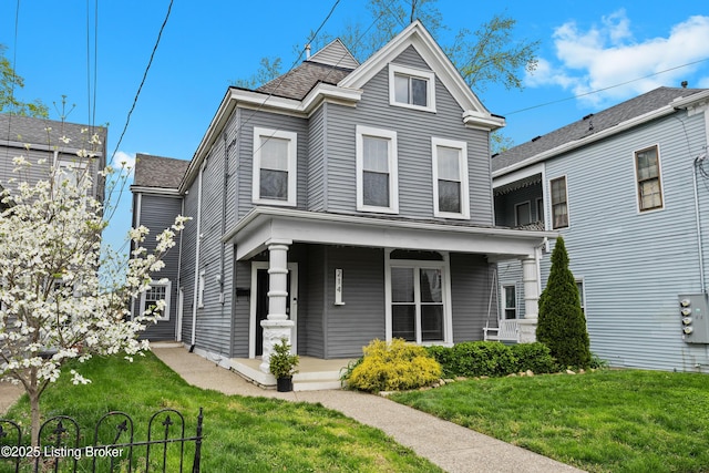 view of front of house featuring a porch, roof with shingles, and a front yard