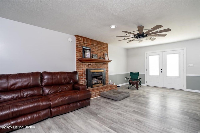 living area with a fireplace, a ceiling fan, wood finished floors, and a textured ceiling