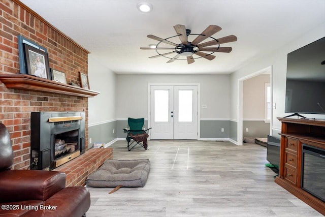 living area featuring a ceiling fan, a fireplace, and light wood-type flooring