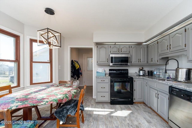 kitchen with an inviting chandelier, gray cabinets, a sink, stainless steel appliances, and light wood-type flooring