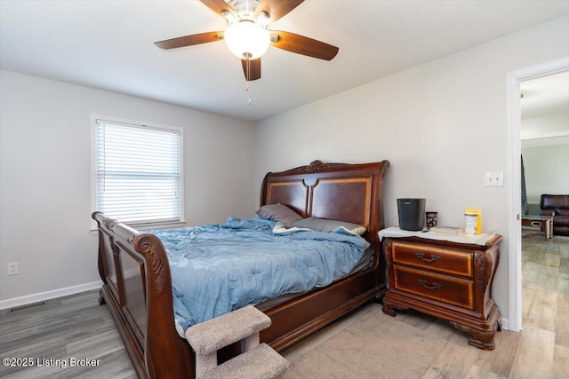 bedroom with a ceiling fan, wood finished floors, visible vents, and baseboards