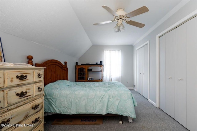 carpeted bedroom with lofted ceiling, a ceiling fan, and multiple closets