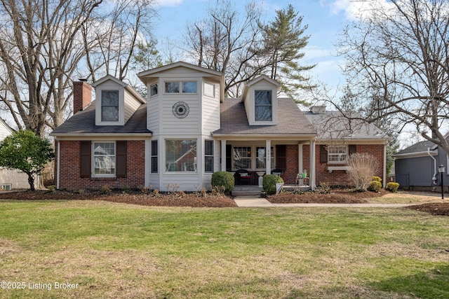 view of front facade with brick siding, covered porch, a chimney, and a front lawn