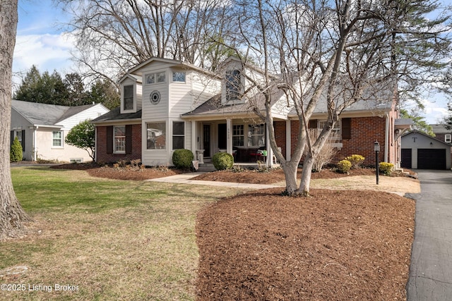 traditional-style house with brick siding, a porch, an outbuilding, and a front lawn