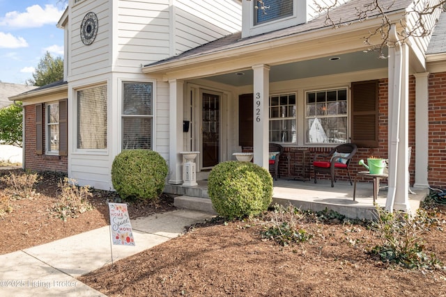 property entrance with brick siding and covered porch